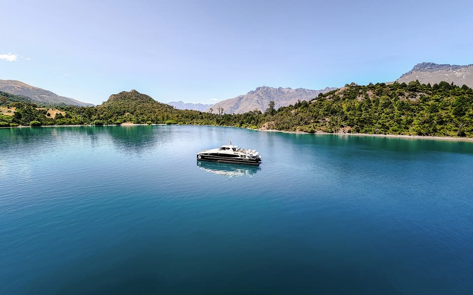 Sleek cruise boat on the blue waters of Lake Wakatipu framed by mountains near Queenstown, New Zealand