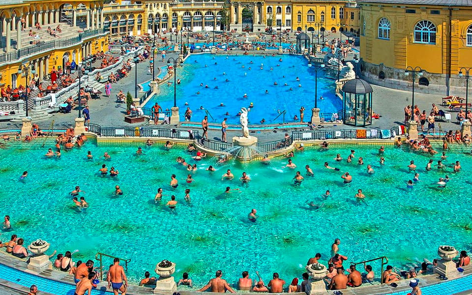 Bathers in the grand outdoor pools of Budapest's Szechenyi Thermal Baths by the yellow palace