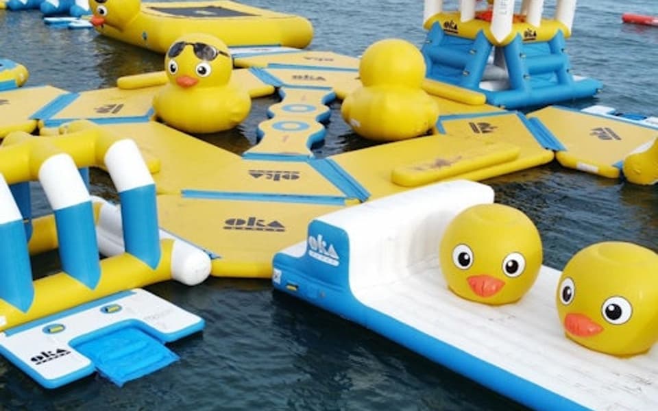 Yellow and blue inflatable water park with giant rubber ducks on the sea at Salou