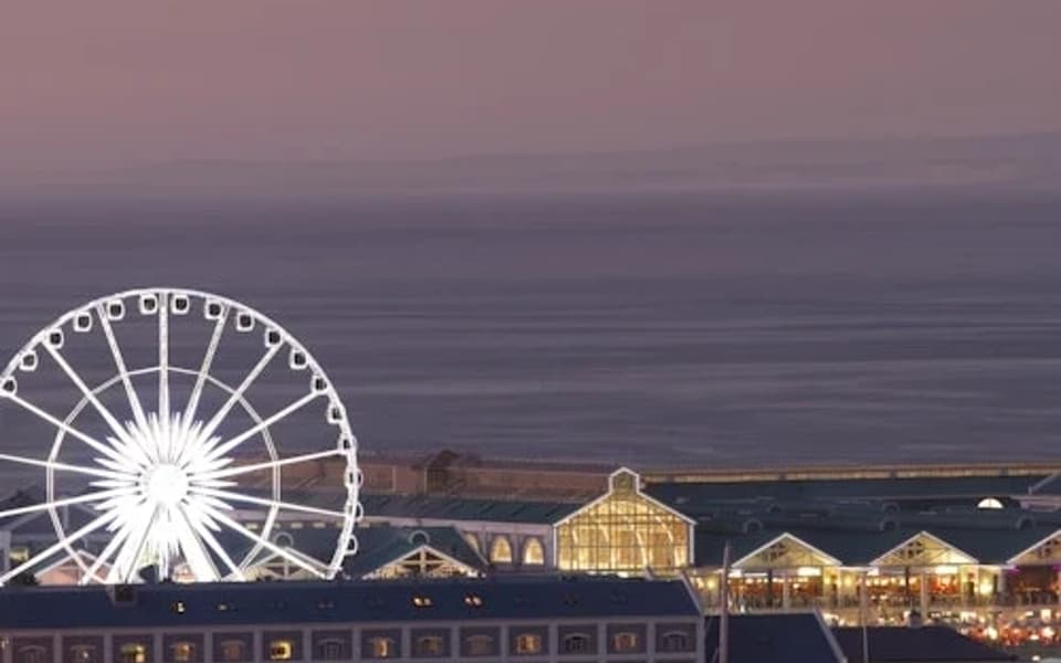 Cape Town V&A Waterfront at dusk with the illuminated Cape Wheel and harbour