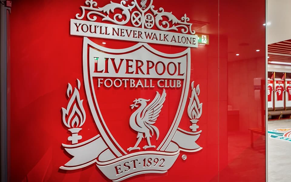 Liverpool FC crest and You'll Never Walk Alone motto on a red dressing-room wall at Anfield