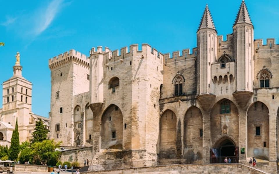 The Palais des Papes medieval stone palace under a blue sky in Avignon, Provence