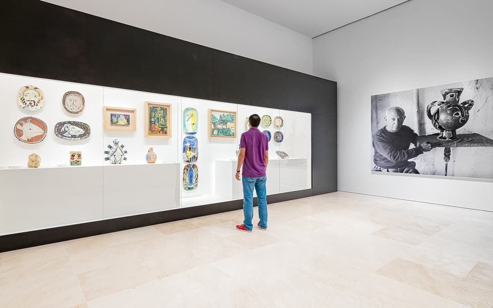Visitor viewing Picasso ceramics and paintings in a bright gallery at the Museo Picasso Malaga
