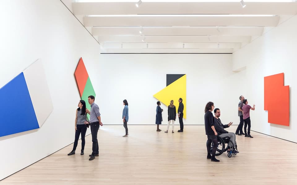 Visitors viewing bold geometric colour-block paintings in a bright San Francisco art gallery