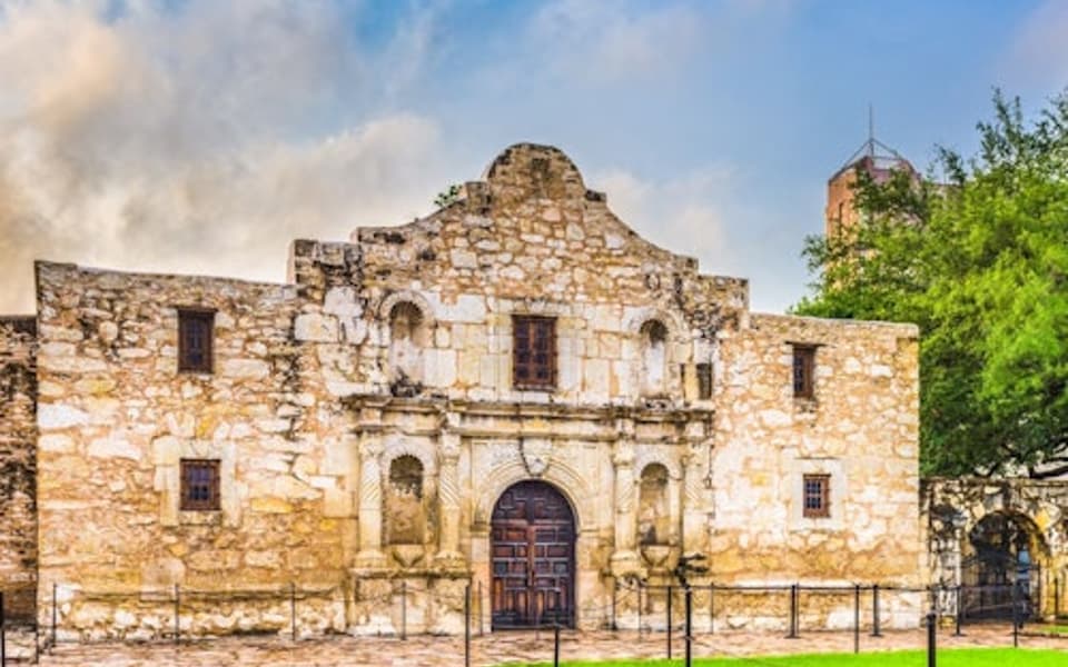 The historic Alamo limestone mission facade under a blue sky in San Antonio