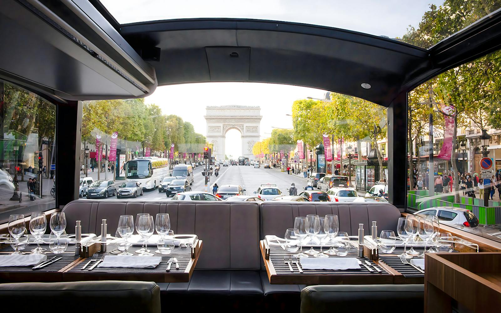 Dining setup inside Bustronome Paris with view of Arc de Triomphe.
