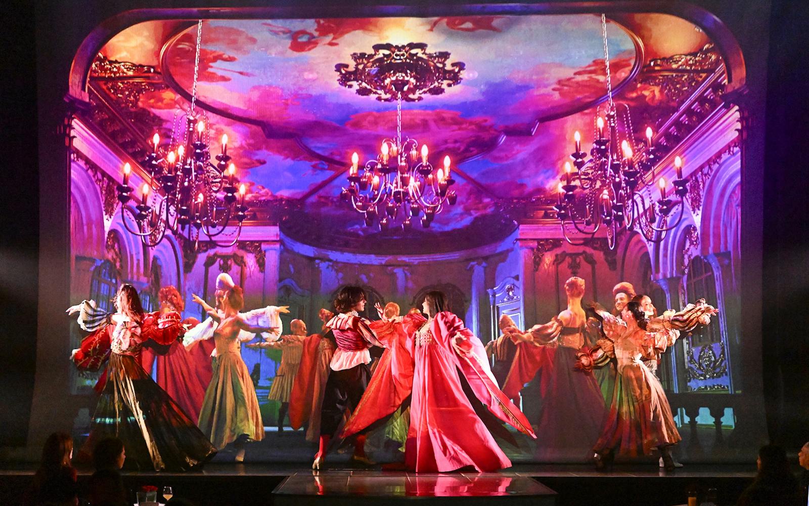 Dancers in vibrant costumes perform on stage at a Paris cabaret with ornate backdrop.