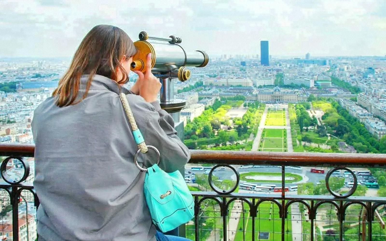 Tourist using telescope to view Trocadero from Eiffel Tower, Paris.