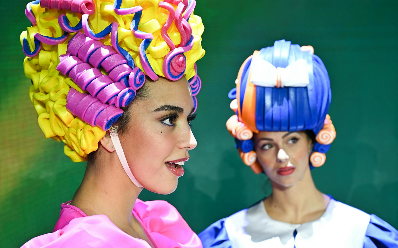 Performers in colorful wigs at Paris cabaret show.