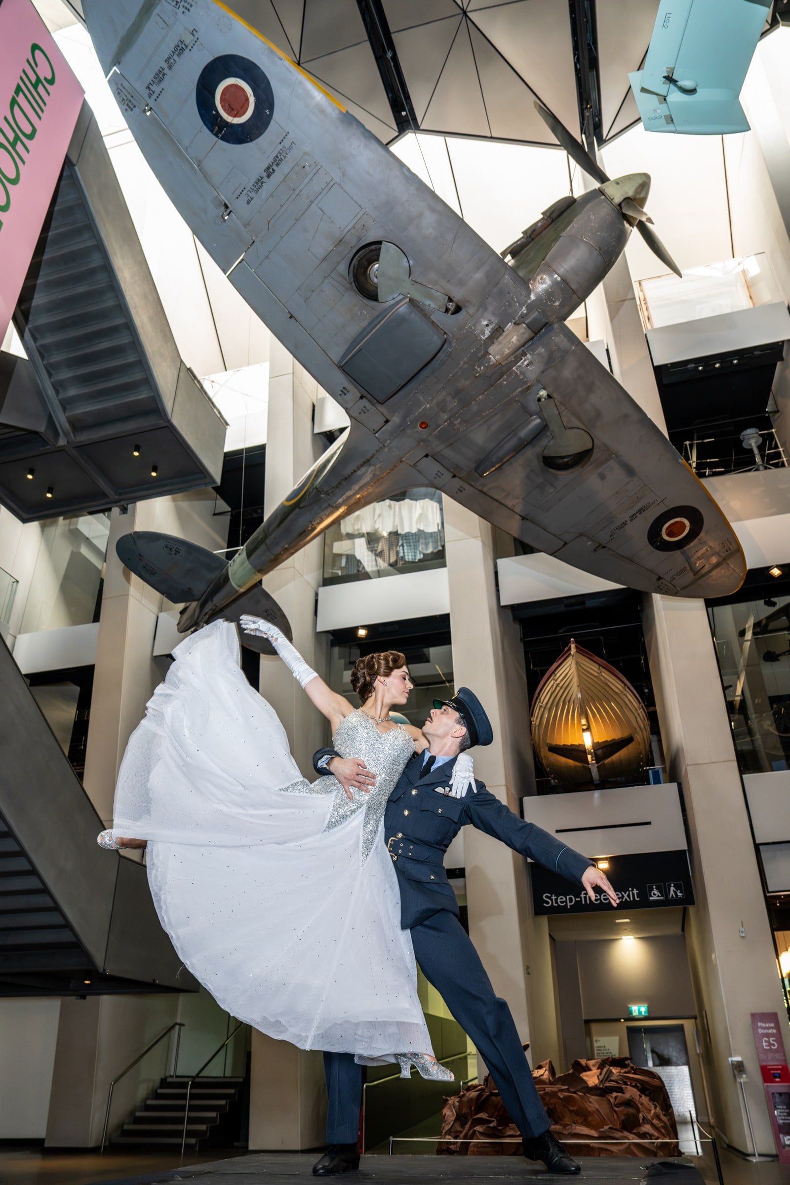 Katrina Lyndon as Cinderella and Reece Causton as Harry the Pilot beneath a Spitfire at IWM London. Photo by Craig Sugden